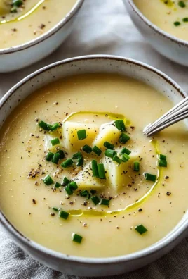Bowl of creamy potato leek soup topped with fresh herbs and croutons.