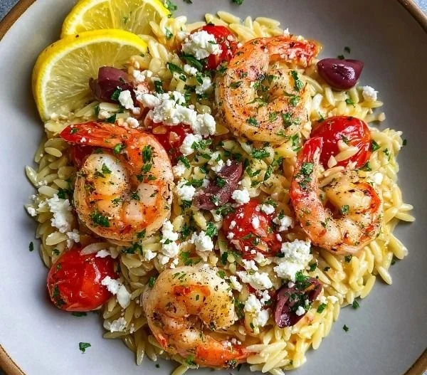 Plate of Lemon Feta Orzo Shrimp garnished with fresh herbs and lemon slices.