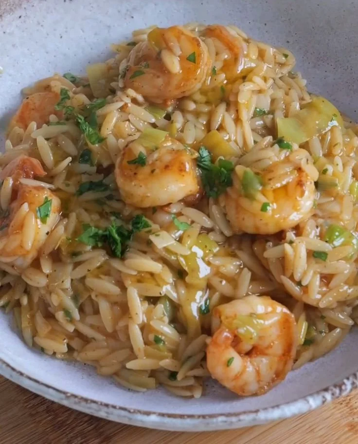 Lemony shrimp orzo dish garnished with fresh herbs and lemon slices