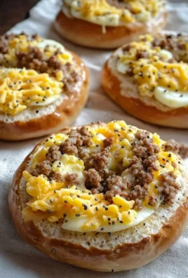 Sausage, egg, and cheese breakfast bagels stacked on a plate