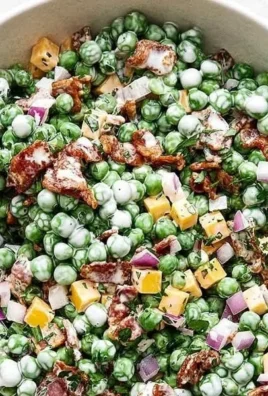 Cold pea salad with bacon served in a bowl with fresh herbs