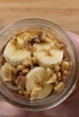Bowl of creamy overnight oats with fresh fruits and nuts on wooden table