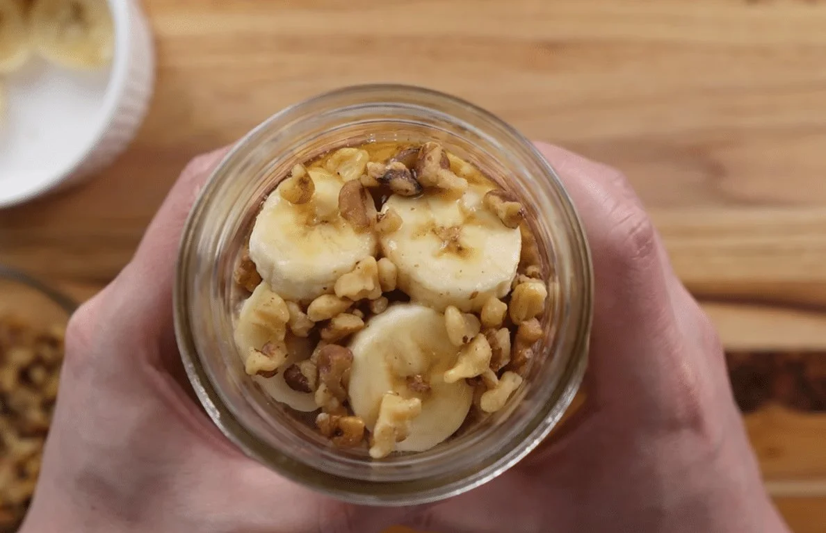 Bowl of creamy overnight oats with fresh fruits and nuts on wooden table