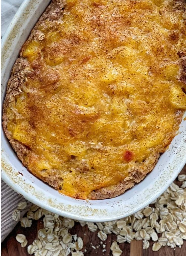 Bowl of Peach Baked Oatmeal topped with fresh peaches and nuts