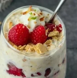 Raspberry Key Lime Pie Overnight Oats bowl topped with fresh raspberries and lime zest
