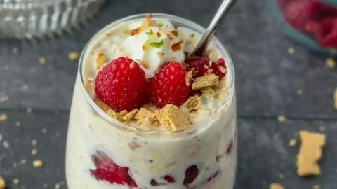 Raspberry Key Lime Pie Overnight Oats bowl topped with fresh raspberries and lime zest