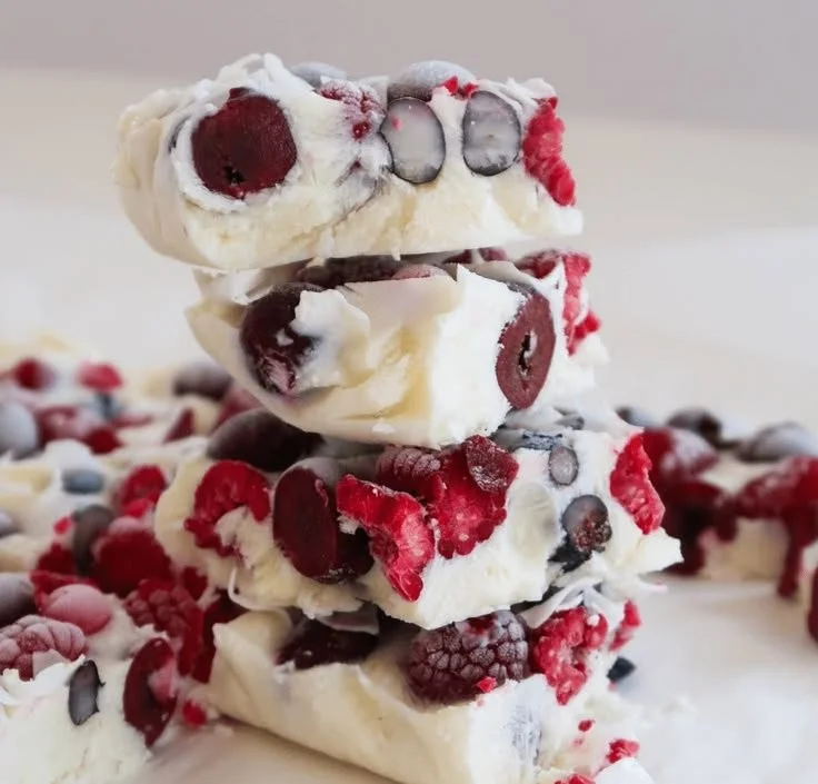 Colorful yogurt bark topped with fruits and nuts on a serving plate.