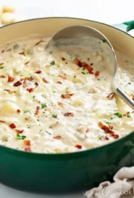 A bowl of creamy clam chowder garnished with parsley and served with a side of oyster crackers.