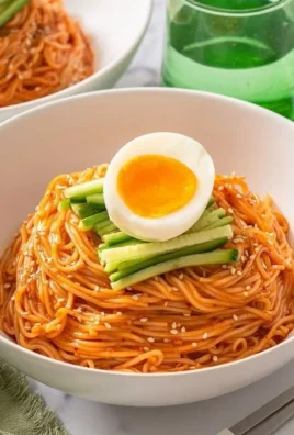 A bowl of Easy Bibim Guksu topped with fresh vegetables and spicy sauce