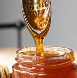 Jar of Easy Hot Honey with a drizzle over spicy chicken wings