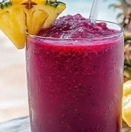 Hibiscus tea pineapple smoothie in a glass with fresh pineapple and ice
