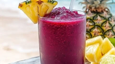 Hibiscus tea pineapple smoothie in a glass with fresh pineapple and ice