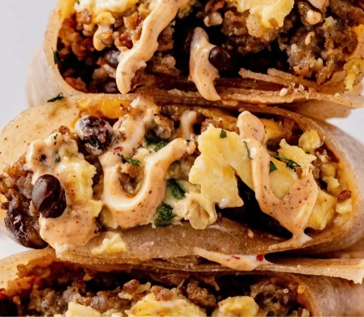 High-protein breakfast burrito filled with eggs, beans, and veggies on a plate.