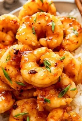 Plate of honey garlic shrimp garnished with green onions and sesame seeds