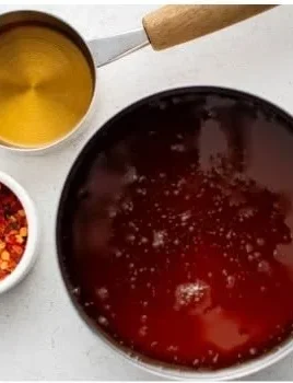 Jar of hot honey with honeycomb and chili peppers.