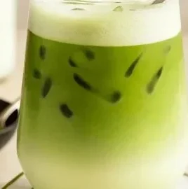 Refreshing iced matcha latte in a glass with ice and green tea powder