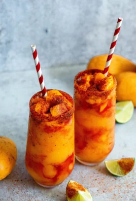 Delicious mango slushies in a glass with ice and a slice of mango