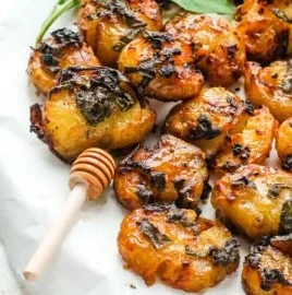Smashed hot honey and sage potatoes served on a plate