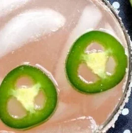 Spicy Paloma cocktail garnished with lime and jalapenos