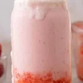 Starbucks Strawberry Cream Frappuccino in a cup garnished with strawberries and whipped cream