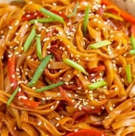 Delicious bowl of sweet and spicy Korean gochujang noodles garnished with fresh vegetables.