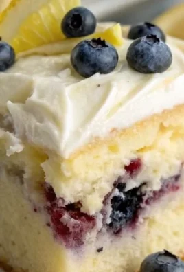 Delicious Blueberry Lemon Poke Cake topped with fresh blueberries and lemon slices
