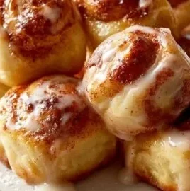 Delicious cinnamon roll bites decorated with icing on a wooden table