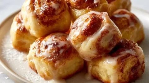 Delicious cinnamon roll bites decorated with icing on a wooden table