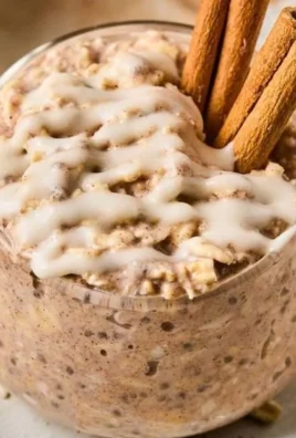 A bowl of cinnamon roll overnight oats topped with cinnamon and nuts