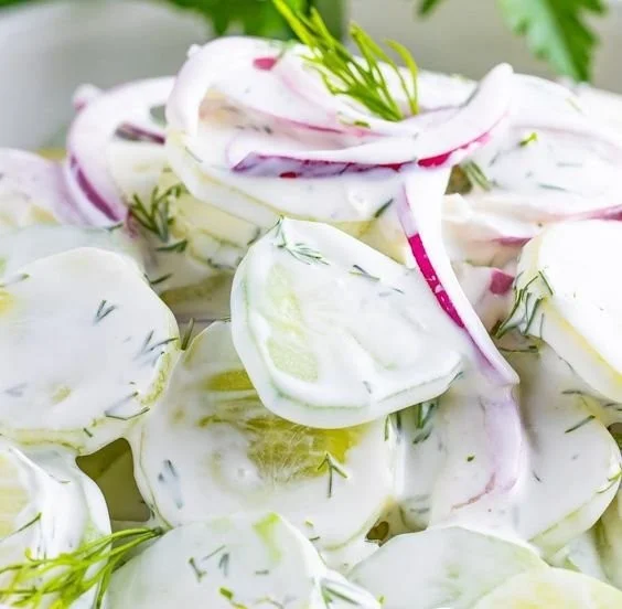 Creamy cucumber salad served in a bowl with fresh herbs and spices
