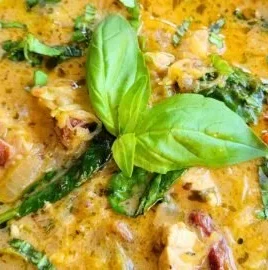 Bowl of creamy gut-healing Tuscan chicken soup garnished with herbs.