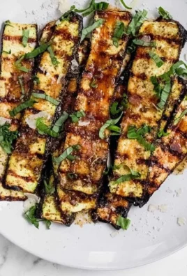 Grilled zucchini topped with Parmesan cheese on a plate.