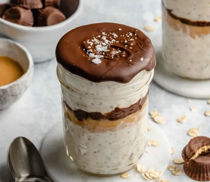 Delicious high-protein peanut butter cup overnight oats topped with chocolate and nuts.