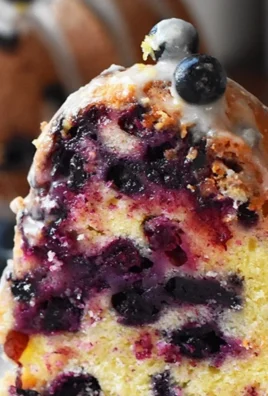 A slice of Lemon Blueberry Bundt Cake adorned with fresh blueberries and lemon zest.