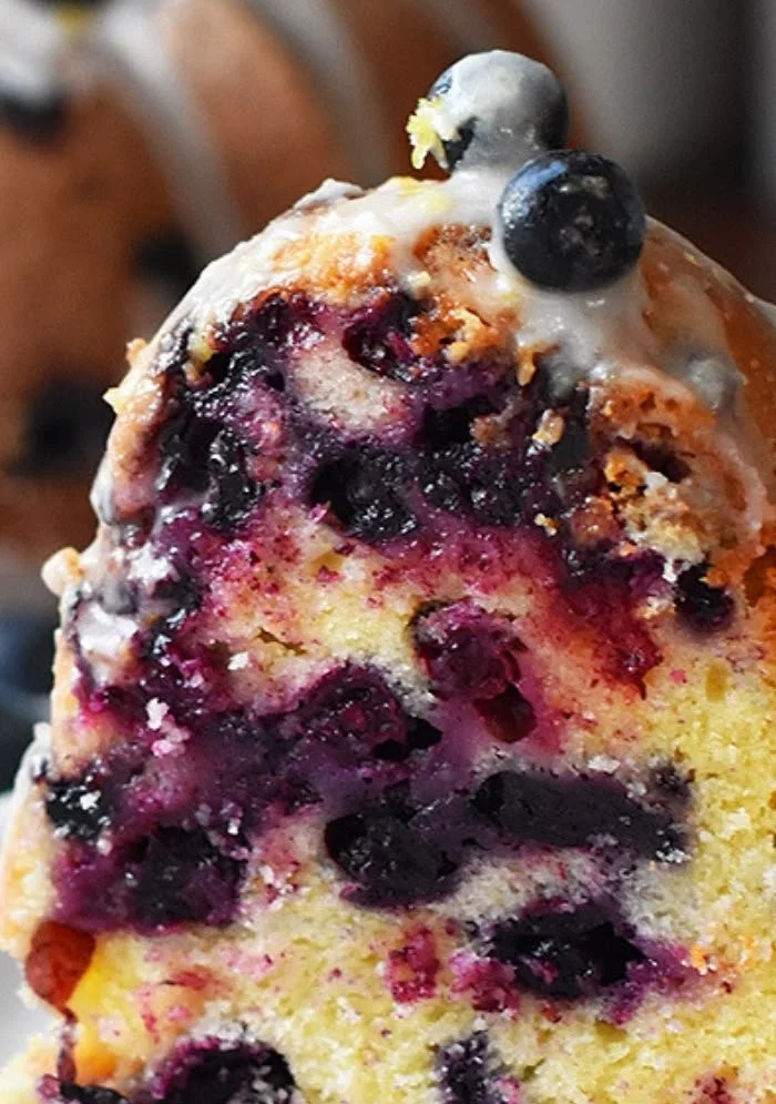 A slice of Lemon Blueberry Bundt Cake adorned with fresh blueberries and lemon zest.