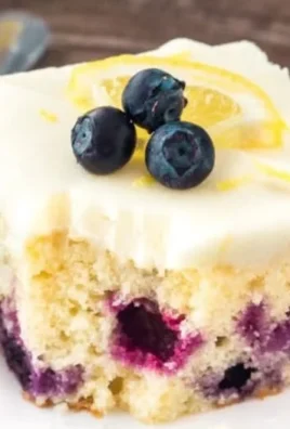 Lemon Blueberry Cake with fresh blueberries and lemon slices on a white plate