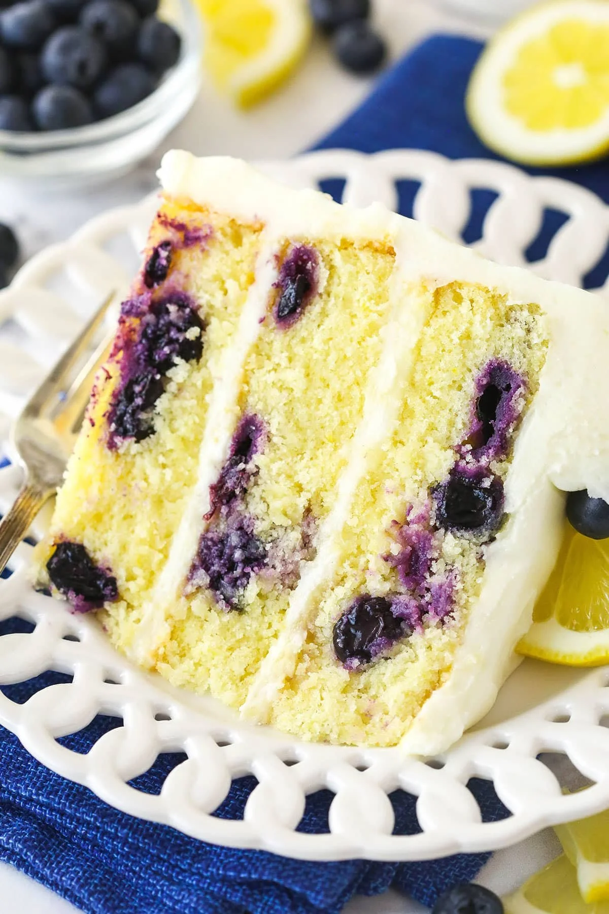 A beautifully decorated Lemon Blueberry Cake with slices revealing juicy blueberries