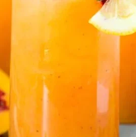 A refreshing glass of peach lemonade with fresh peach slices and lemon wedges
