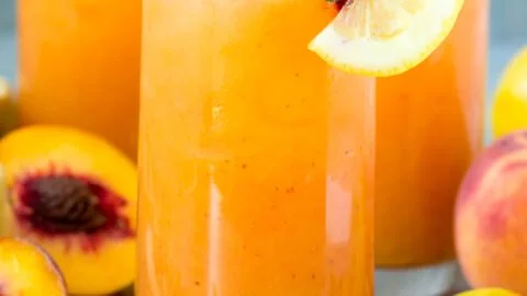 A refreshing glass of peach lemonade with fresh peach slices and lemon wedges