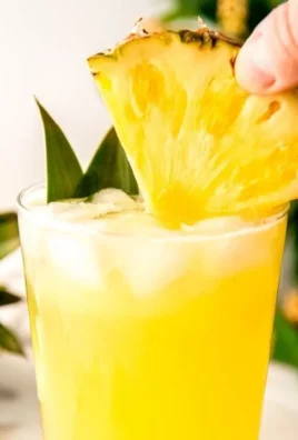 Glass of refreshing pineapple lemonade with lemon slices and a pineapple wedge
