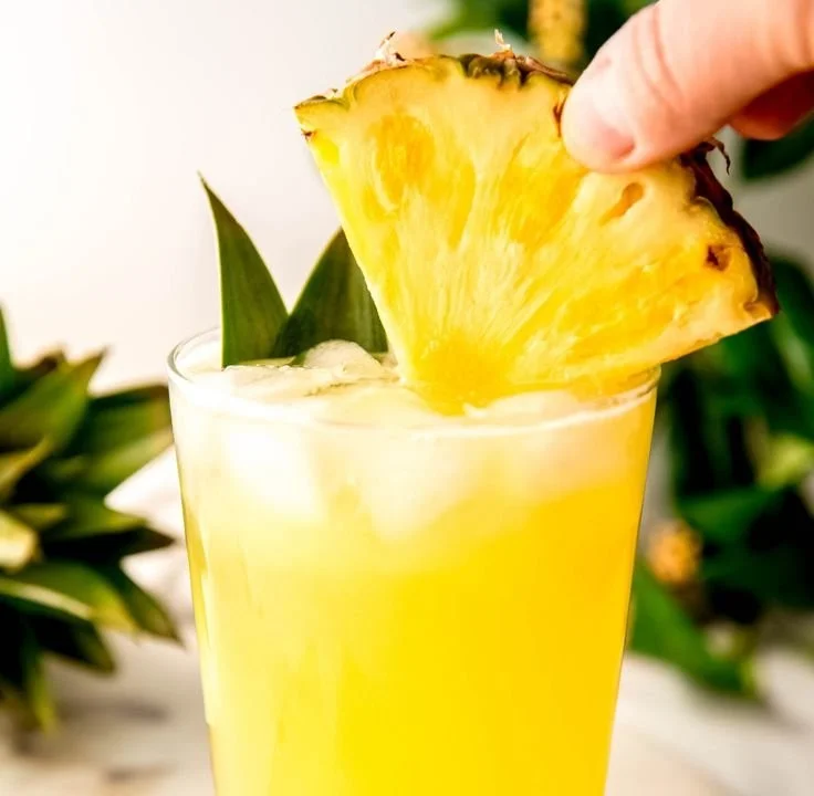 Glass of refreshing pineapple lemonade with lemon slices and a pineapple wedge