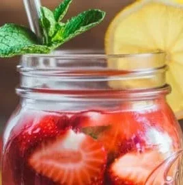Freshly made strawberry lemonade in a glass with lemon slices and strawberries