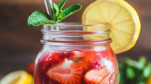 Freshly made strawberry lemonade in a glass with lemon slices and strawberries