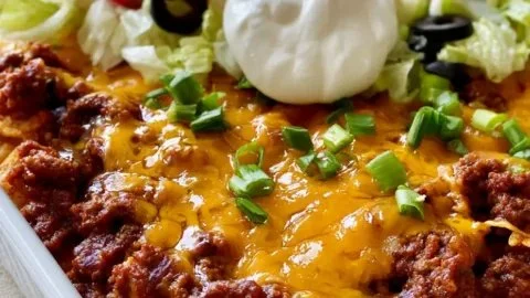 Delicious Walking Taco Casserole topped with cheese and crunchy toppings